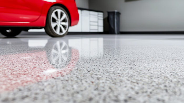 Epoxy flooring in a garage with a red car in El Paso.